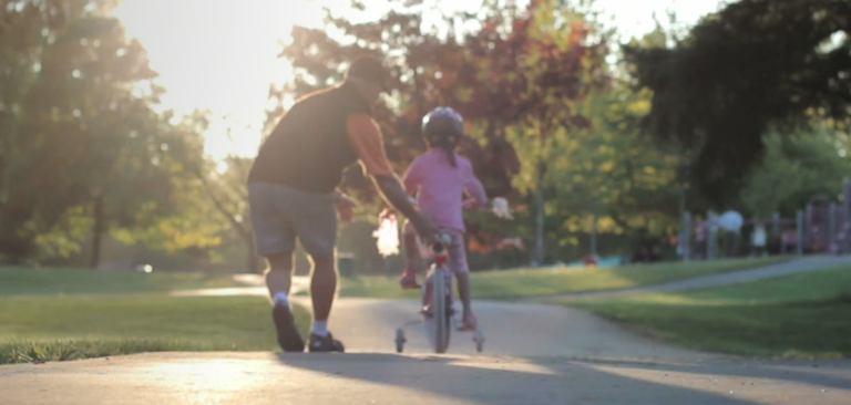 padre ayudando a a su hija a conducir en bicicleta