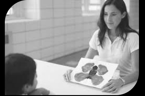 Psicóloga mostrando láminas de test proyectivo a un niño durante una evaluación