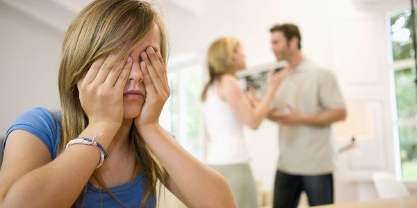 niña tapandose la cara y sufriendo por las peleas de sus padres