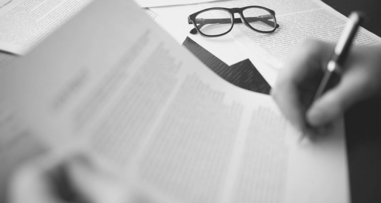 Documentos y anteojos sobre un escritorio, redacción de un informe pericial