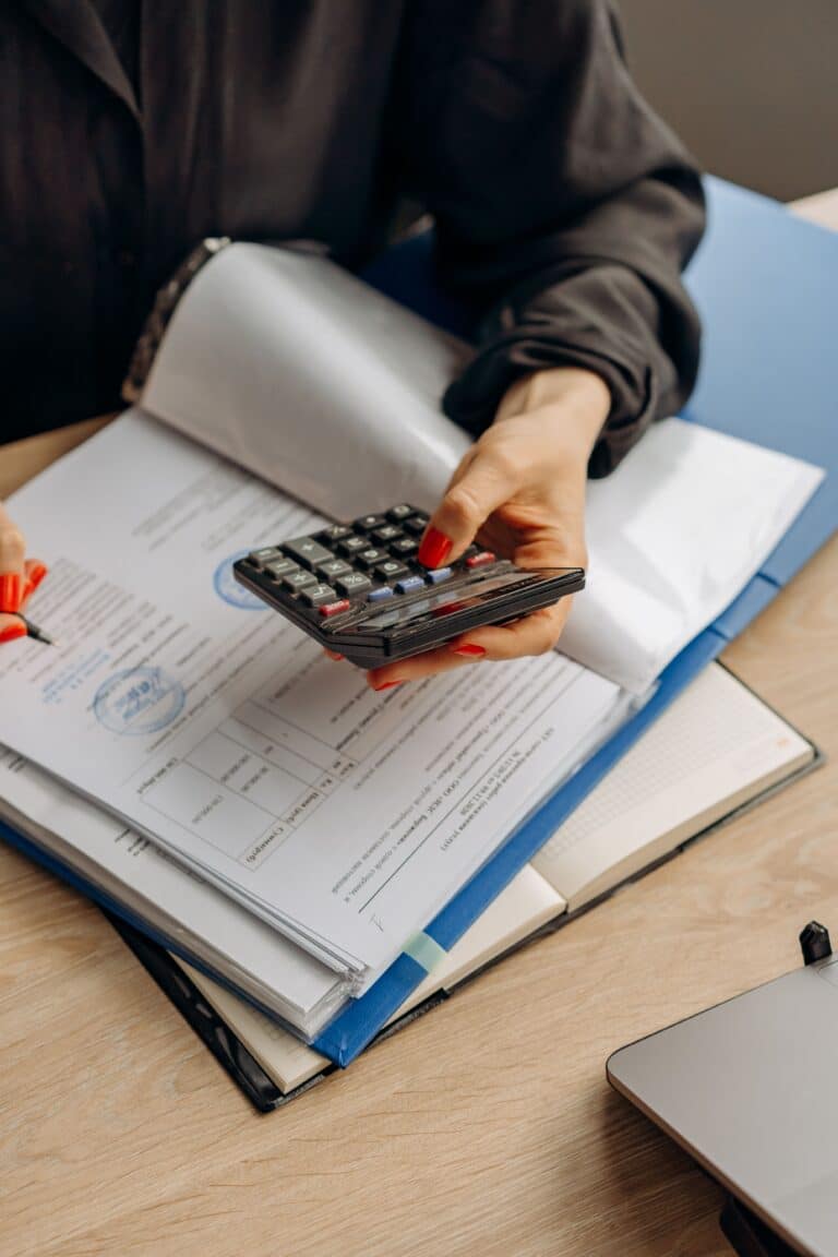 Persona utilizando una calculadora sobre documentos financieros