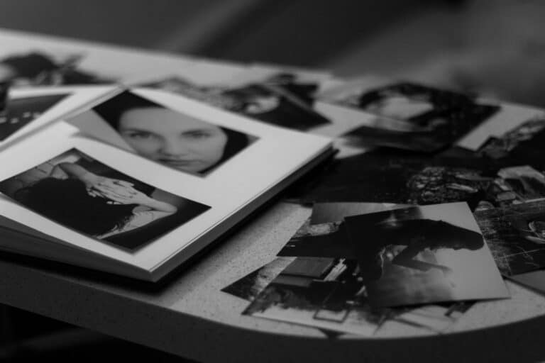Fotografías en blanco y negro dispersas sobre una mesa, en referencia a las láminas del test de apercepción temática (TAT)