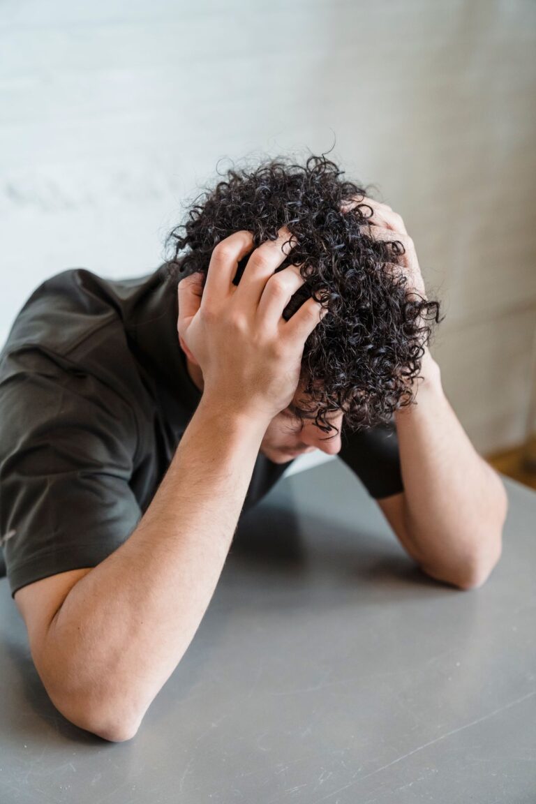 Hombre apoyado sobre una mesa con la cabeza entre las manos, expresando frustración